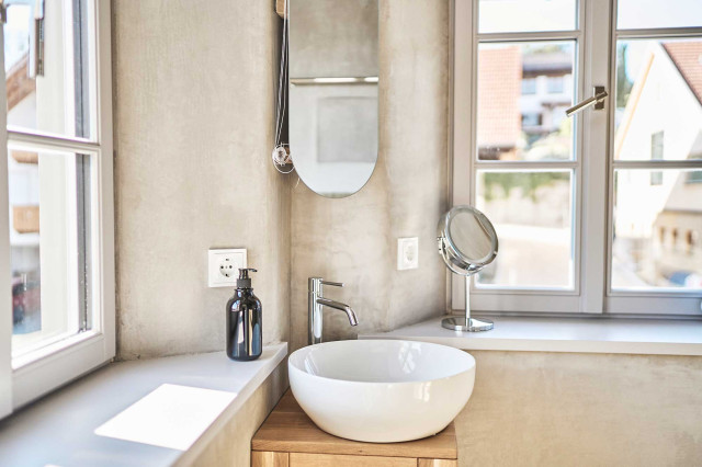 Boutique Apartment Bergfreuden - Badezimmer mit natürlichem hellgrauen Kalkputz gespachtelten Wänden, abgerundeten Fensterlaibungen, weißen Sprossenfenstern, einem kleinen Waschtisch aus Eichenholz und ein kleines, rundes, weißes Keramikwaschbecken (Photo 9)