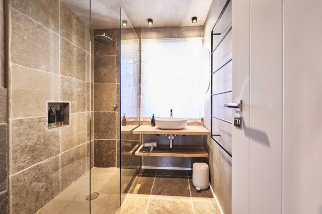 Das Flachshaus Ferienhaus - Badezimmer mit Natursteinboden und Natursteindusche aus Muschalkalkstein, Duschabtrennung aus Glas, Waschtisch aus massiven Eichenholzbrettern mit weißem Keramikwaschbecken (Photo 13)