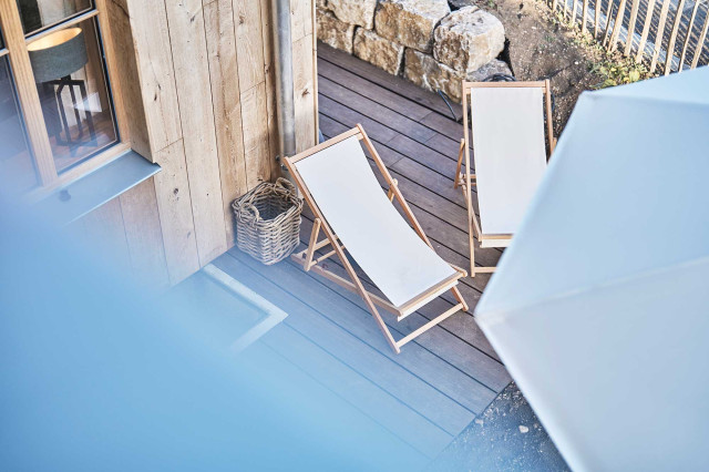 Boutique Apartment Flachsblüte - Holzterrasse mit weißen Deckchairs an Holzfassade (Photo 12)