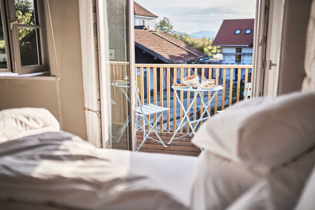 Das Flachshaus Ferienhaus - Blick aus einem Schlafzimmer mit geöffneten bodentiefen Fenstern Richtung modernem Holzbalkon, auf dem ein hellblaues Bistro-Set steht (Photo 20)