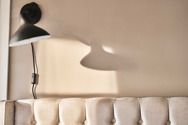 Das Flachshaus Ferienhaus - Schwarze Industrial Design Wandleuchte über samtigem, sandfarbenem Chesterfield-Bettrücken (Photo 23)