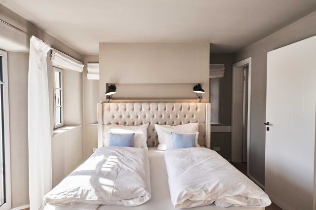 Das Flachshaus Ferienhaus - Helles Schlafzimmer mit Boxspringbett im Chesterfield-Design, gestärkter weißer Bettwäsche (Photo 32)