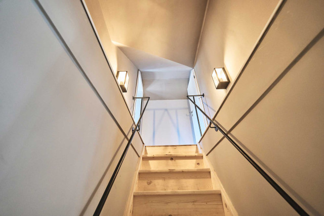 Das Flachshaus Ferienhaus - Schmale Holzstiege mit handgefertigtem schwarzen Stahlgeländer, hellgrauen Wänden und modernen Wandlaternen aus Glas mit schwarzem, filigranem Stahlrahmen (Photo 51)