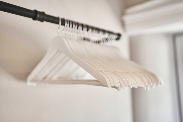 Boutique Apartment Flachsblüte - Schwarze Stahlrohr-Kleiderstange mit weißen Kleiderbügeln an hellgrauer Wand (Photo 26)