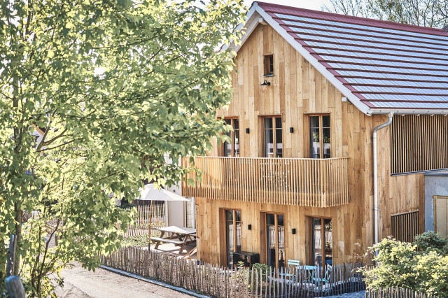 Boutique Apartment Bergfreuden - Ferienhaus mit moderner Holzgiebelfassade, Holzbalkon mit schlichten Sprossen und seitliche Holzfassade mit Holzlamellen, sowie ein mit roten Solardachziegeln gedecktes Dach (Photo 26)