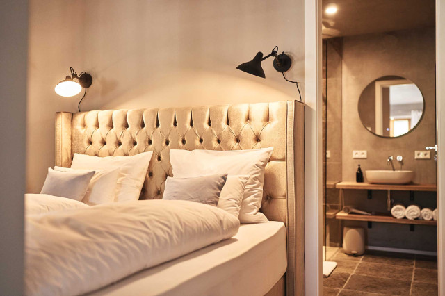 Boutique Apartment Flachsblüte - Boxspringbett mit weißer, gestärkter Hotellbettwäsche, Chesterfield-Design Bettrücken und warm leuchtenden schwarzen Industrial Design Wandleuchten (Photo 7)