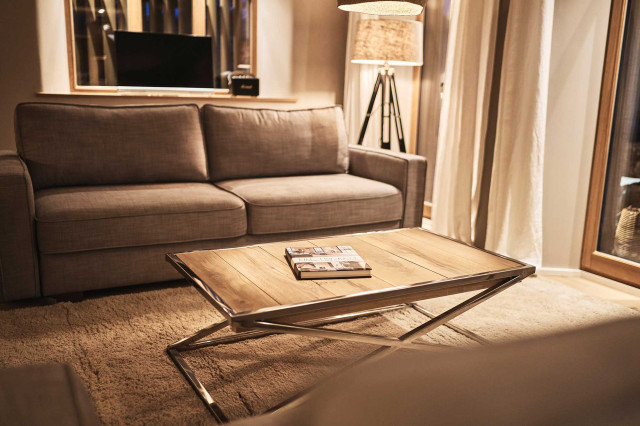 Boutique Apartment Flachsblüte - Gemütlich beleuchtetes Wohnzimmer mit hellgrauem Sofa, flauschigem beigem Teppich, verchromter Couchtisch mit Eichenholzdielen als Tischplatte, sowie in der Ecke eine Tripod-Stehleuchte mit schwarzem Leuchtenfuß und grauem, durchschimmernden Leuchtenschirm (Photo 45)